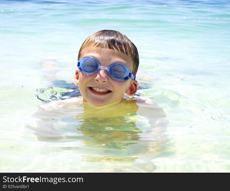 a child swimming in the ocean with goggles. a child swimming in the ocean with goggles