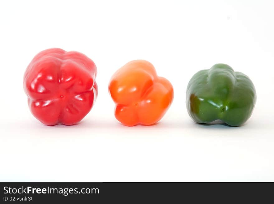 Green, orange and red bell peppers above white. Green, orange and red bell peppers above white