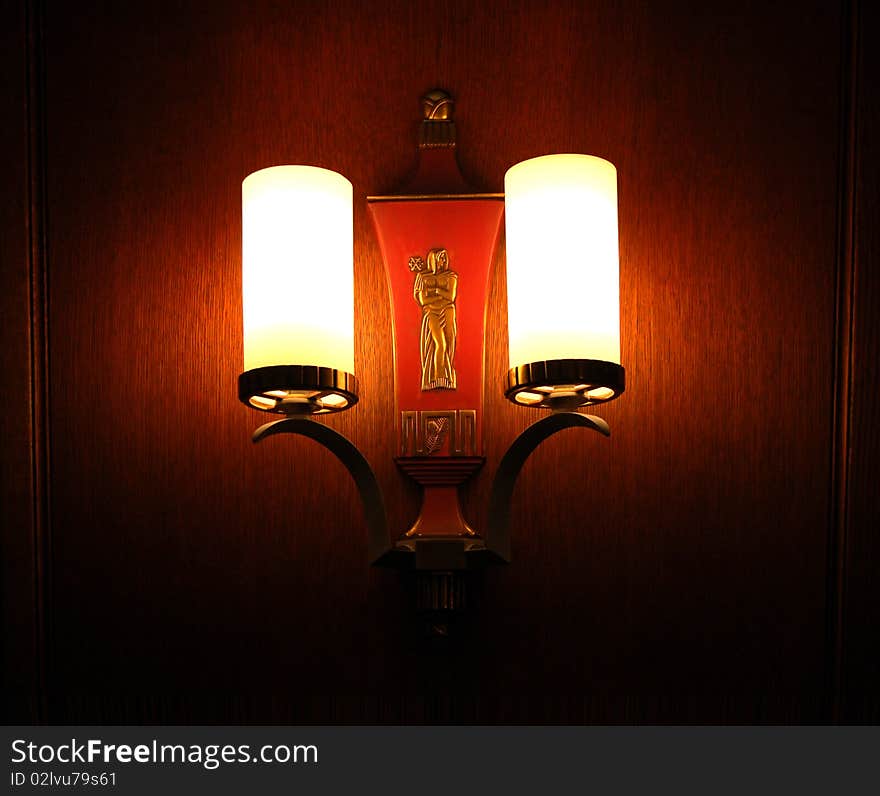 Vintage wall sconce in darkened room, with sculpture