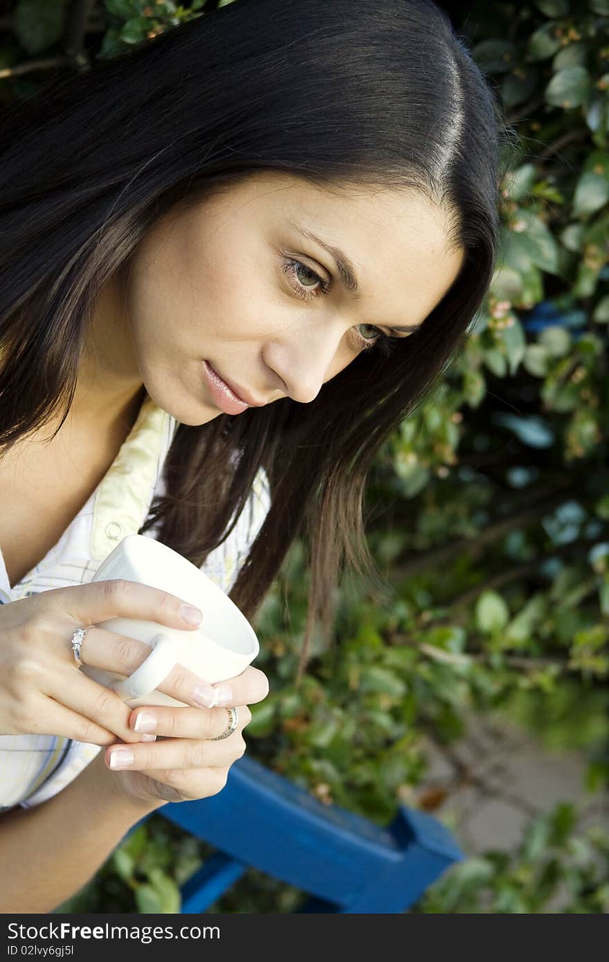 Teen girl resting in a park sitting on a bench in the hands of a white cup with coffee. Teen girl resting in a park sitting on a bench in the hands of a white cup with coffee