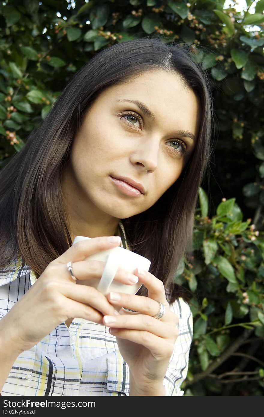 Teen girl resting in a park sitting on a bench in the hands of a white cup with coffee. Teen girl resting in a park sitting on a bench in the hands of a white cup with coffee