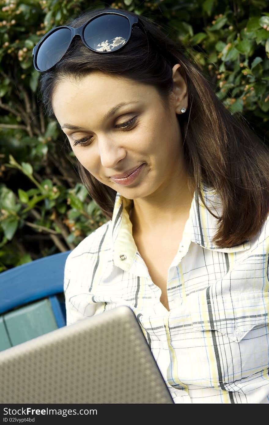 Young woman sits on a wooden park bench with laptop. Young woman sits on a wooden park bench with laptop