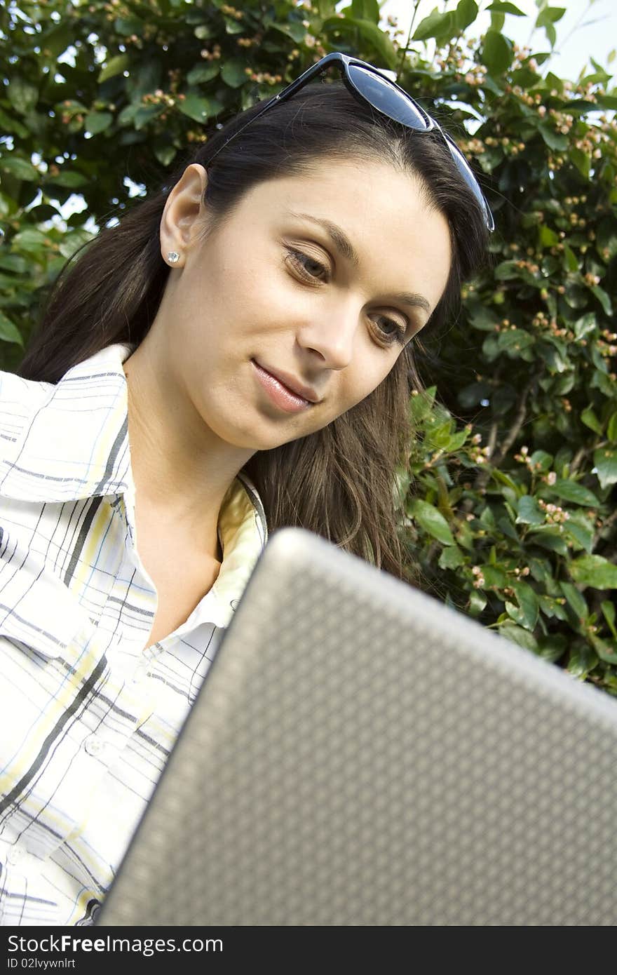 Young woman sits on a wooden park bench with laptop. Young woman sits on a wooden park bench with laptop