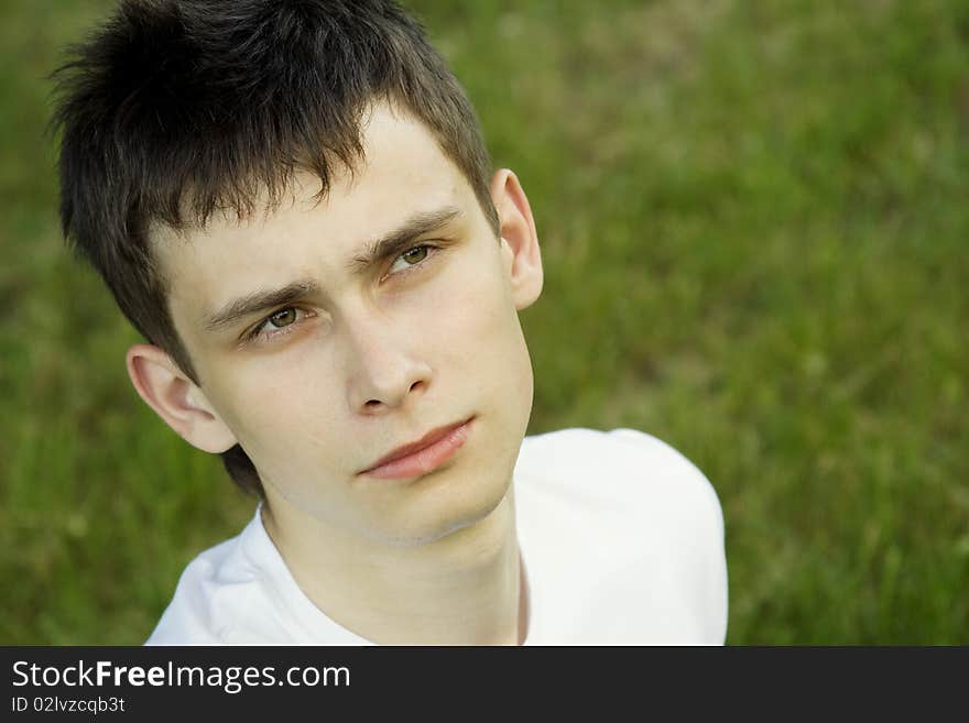 Teenager resting in a park sitting on the lawn looks to the future. Teenager resting in a park sitting on the lawn looks to the future