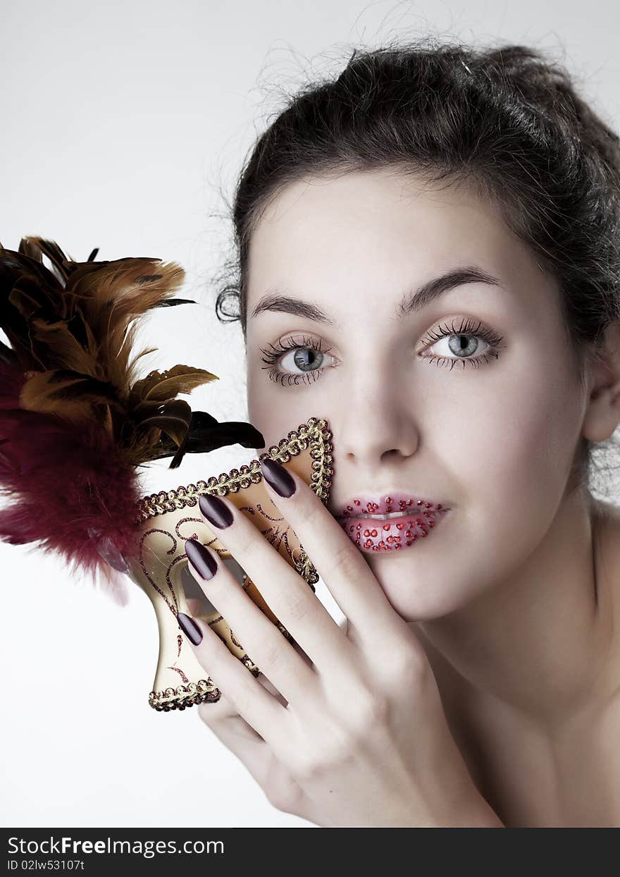 The image of a beautiful girl with a carnival mask in the hands