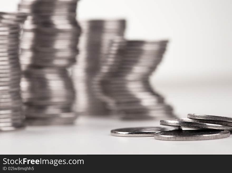 Coins against stacks of coins, casting shadow on white.