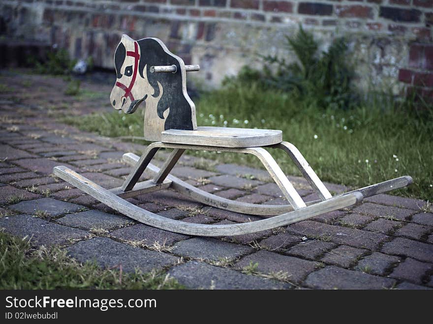 Vintage children's rocking horse outside a farm house.