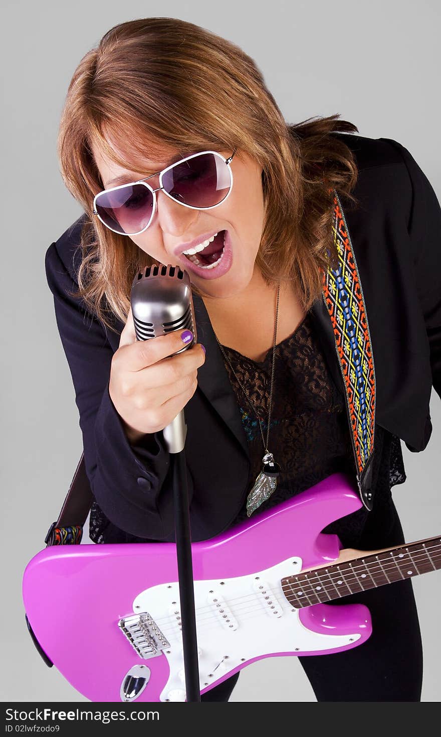 A pretty young woman with a guitar and microphone sings a song. A pretty young woman with a guitar and microphone sings a song.