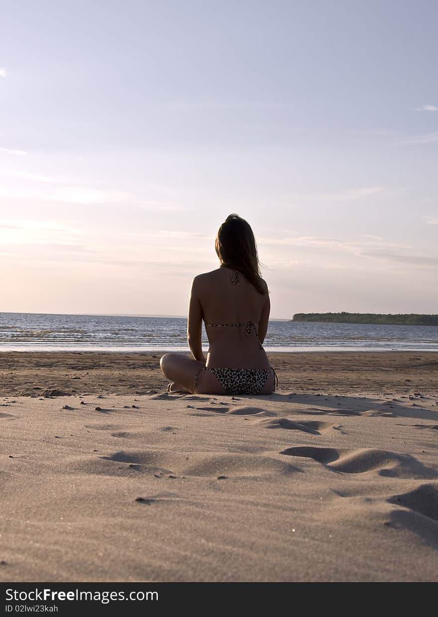 Young girl sitting on a deserted beach