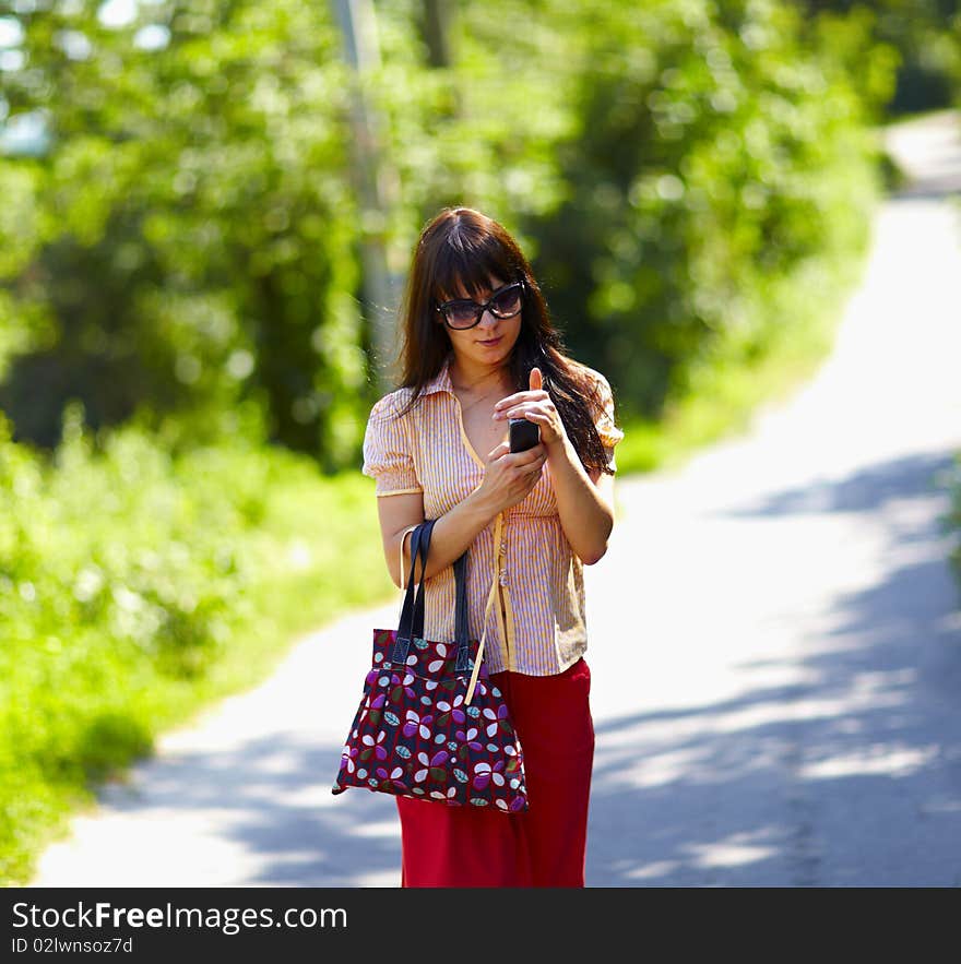 Cute girl walking the street in the park and using her mobile phone. Cute girl walking the street in the park and using her mobile phone