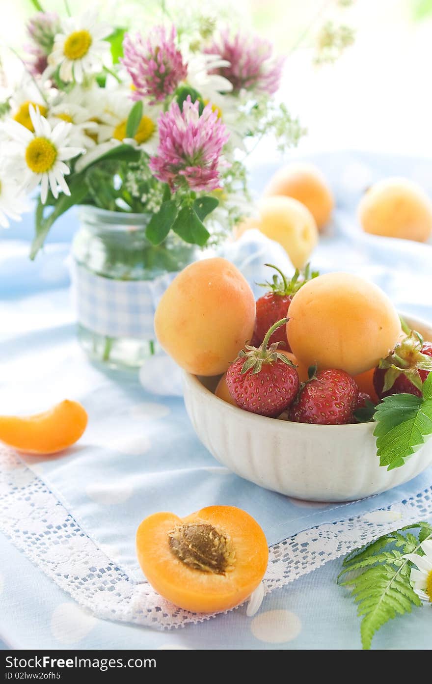 Fresh apricots and strawberries in and beside bowl