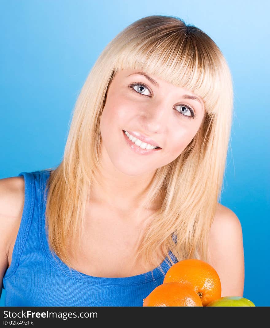 Portrait of young woman with orange and apple in her hands