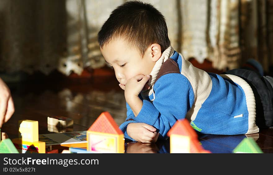 The little Asian boy playing toy bricks in house