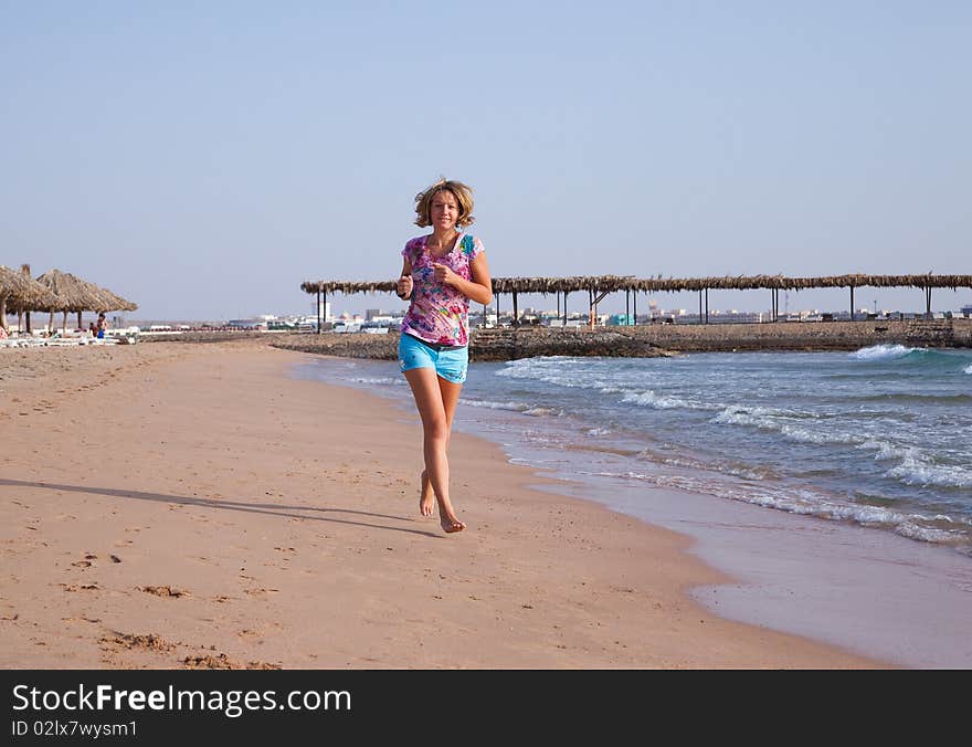 Beautiful young woman running on a beach