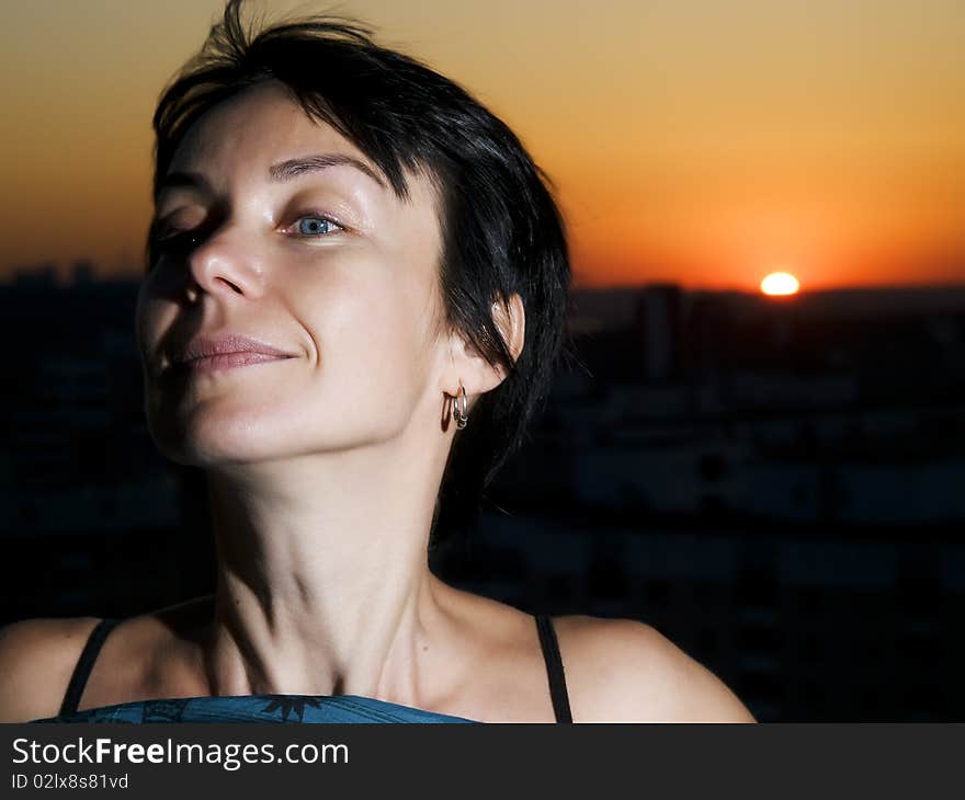 Woman on a cities roof against a sunset. Woman on a cities roof against a sunset