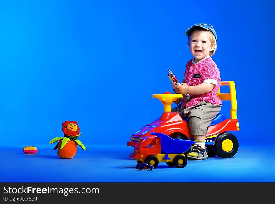 The portrait of a happy little boy playing with toy cars