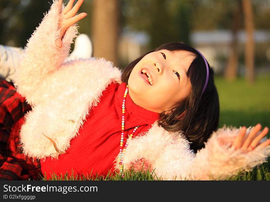 The little Chinese girl laughing on the grass in autumn. The little Chinese girl laughing on the grass in autumn