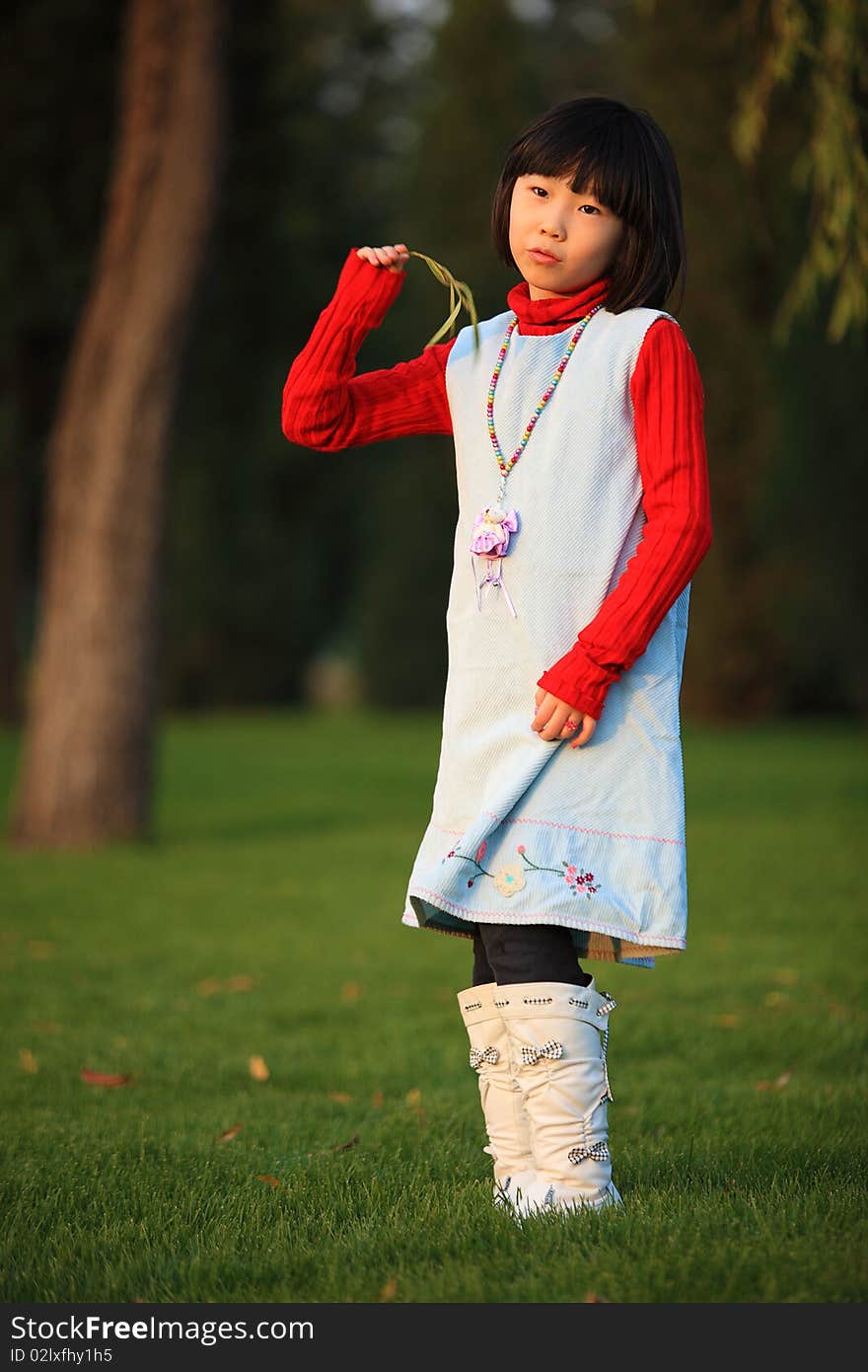 The little Chinese girl standing outside in autumn. The little Chinese girl standing outside in autumn