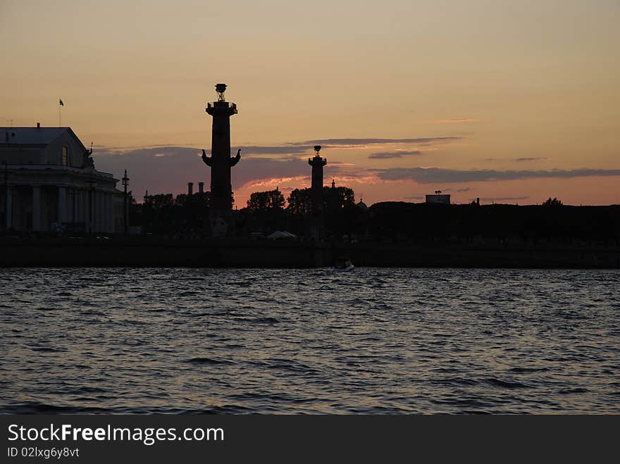 White Nights of Saint-Petersburg. Russia.  View of the Neva river and silhouettes of Rostral Columns on Vasilyevsky island. White Nights of Saint-Petersburg. Russia.  View of the Neva river and silhouettes of Rostral Columns on Vasilyevsky island.