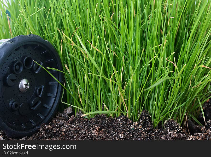 Green grass requiring in Irrigation, nearby near a grass a water spray for Irrigation.