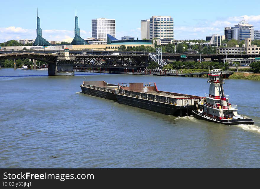 A push boat and barges traveling on the Willamette river through bridges near downtown Portland Oregon. A push boat and barges traveling on the Willamette river through bridges near downtown Portland Oregon.