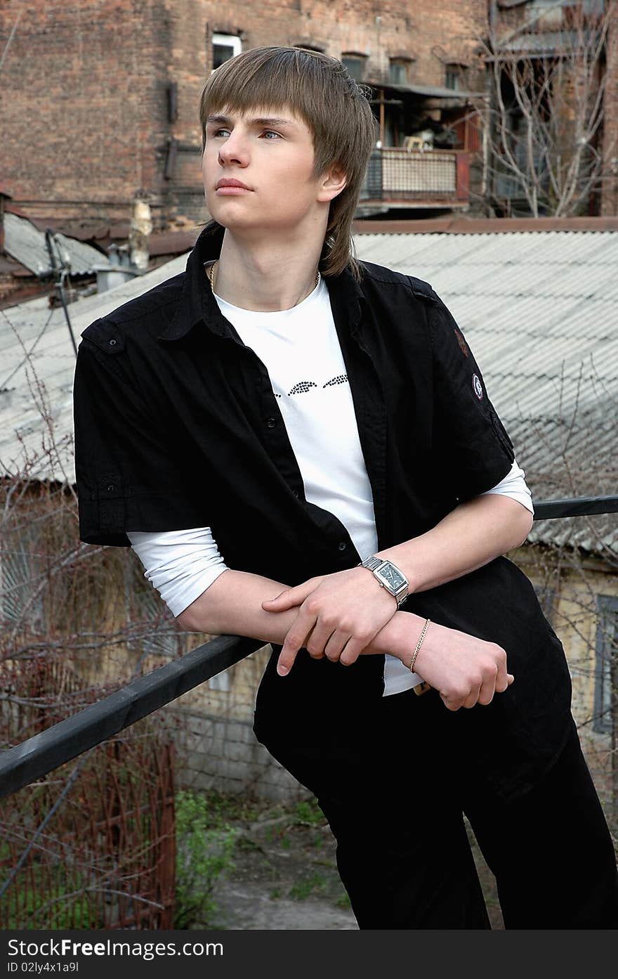 Seriously stylish man with blond hair in black and white shirt with a clock on the hand