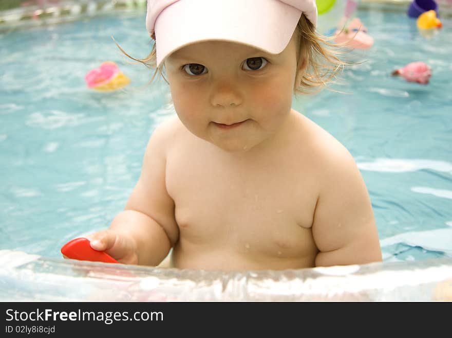 The beautiful child in a cap with the big eyes sits in pool. The beautiful child in a cap with the big eyes sits in pool