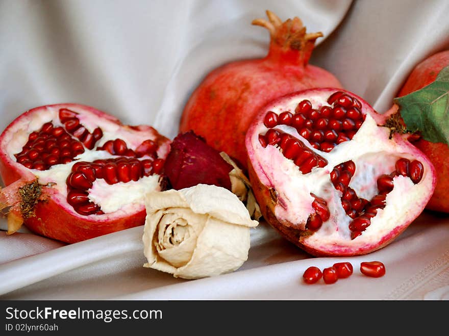 Pomegranates whole and seeded with dry roses