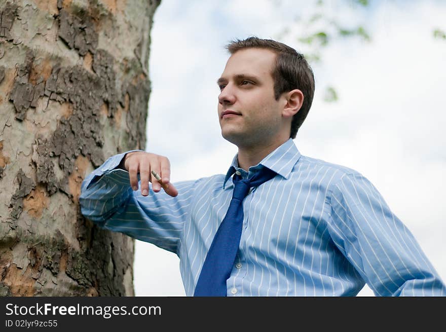 Young Businessman Leaning Against A Tree