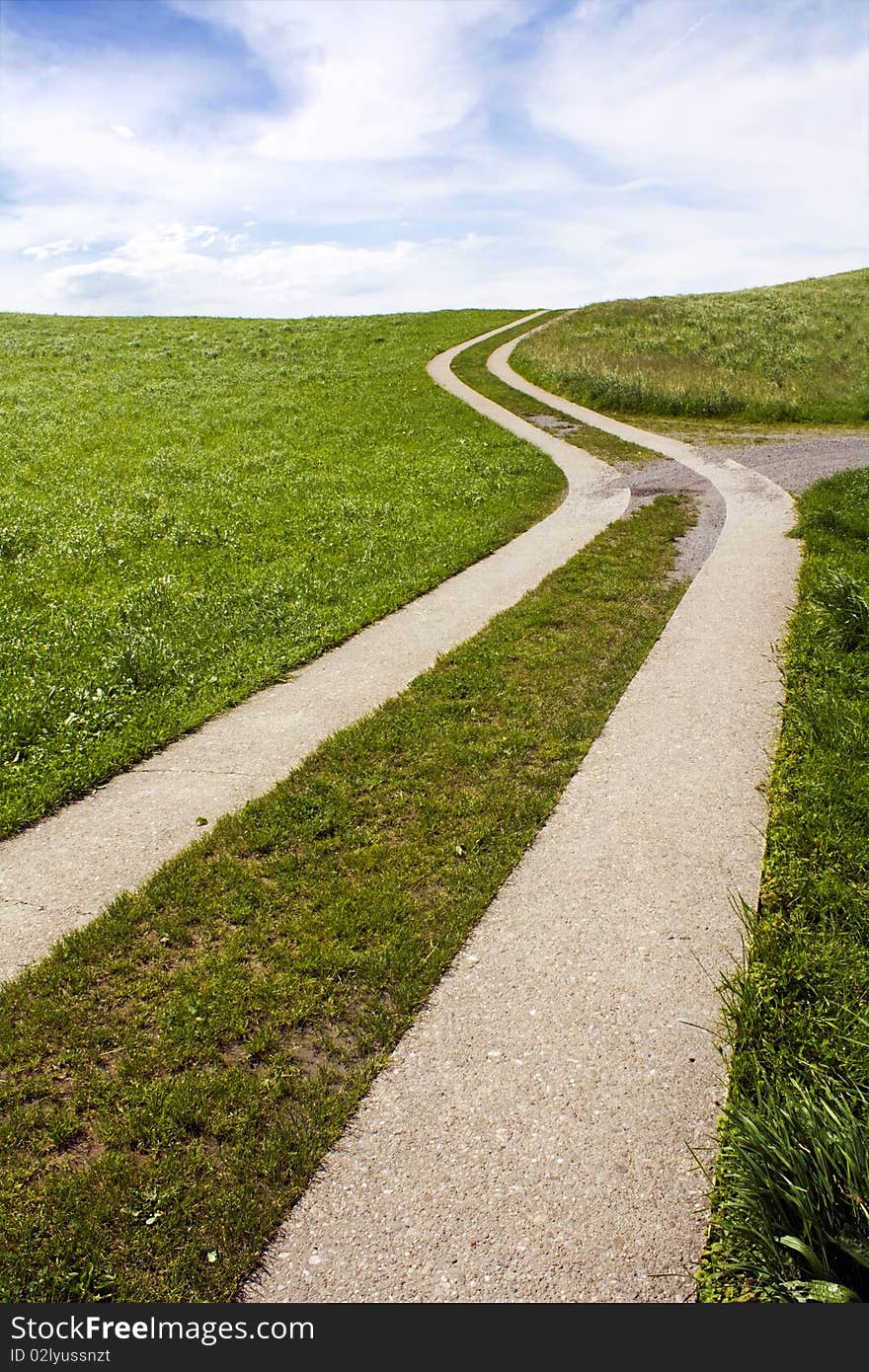 Snaky path in the green grass with nice cloudy sky in back. Snaky path in the green grass with nice cloudy sky in back