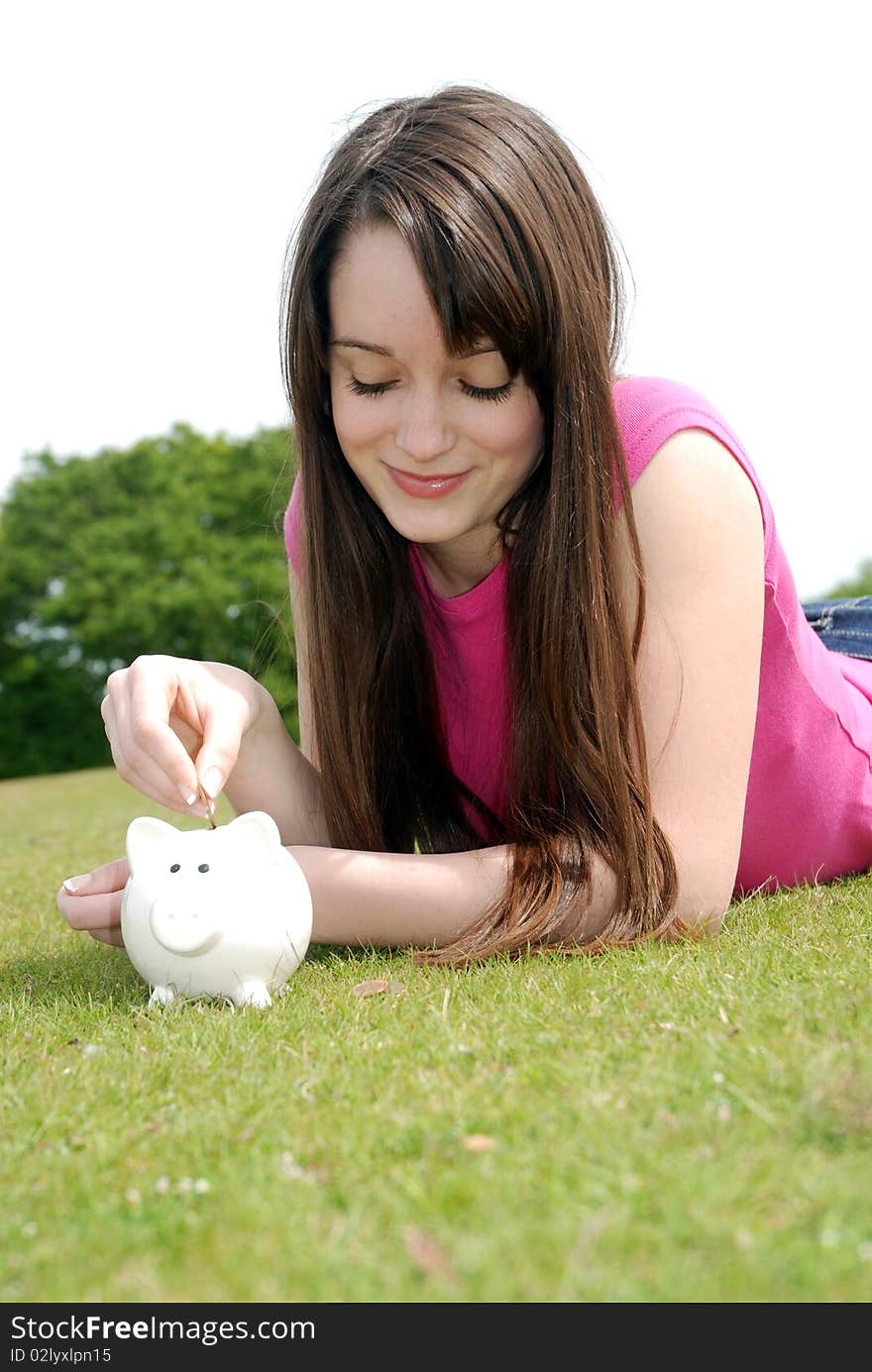 Young woman putting coin in piggy bank. Young woman putting coin in piggy bank