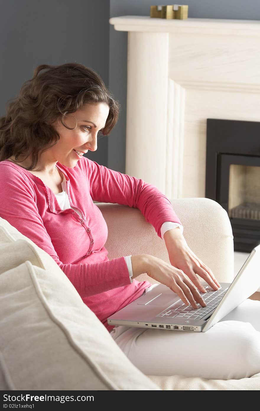 Woman Using Laptop Relaxing Sitting On Sofa At Home