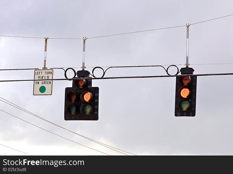 Traffic stoplights suspended over road, the signal is yellow and means yield, proceed with caution. Traffic stoplights suspended over road, the signal is yellow and means yield, proceed with caution.