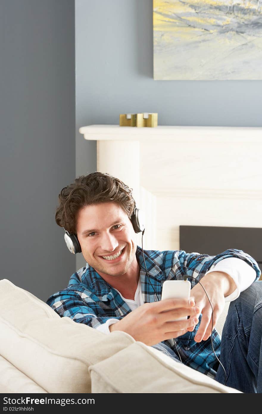 Man Listening To MP3 Player On Headphones Relaxing Sitting On Sofa At Home. Man Listening To MP3 Player On Headphones Relaxing Sitting On Sofa At Home