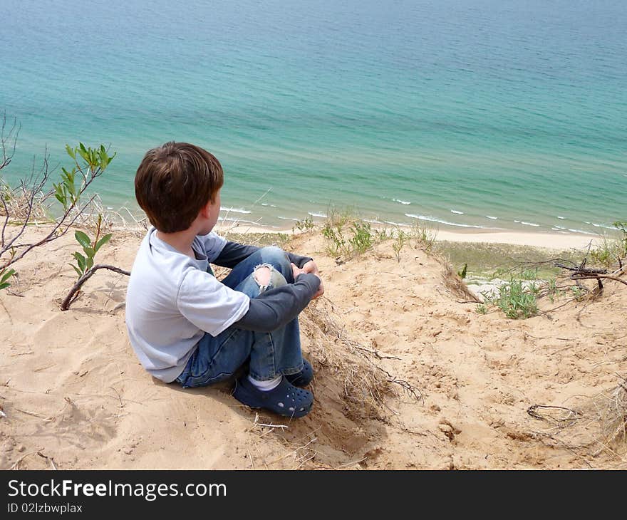 A young boy sitting atop a bluff looking down at Lake Michigan. A young boy sitting atop a bluff looking down at Lake Michigan.