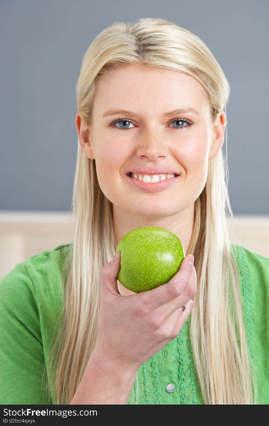 Woman Relaxing On Sofa Eating Apple At Home