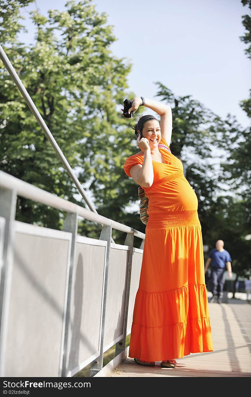 Happy pregnant woman talking by cellphone