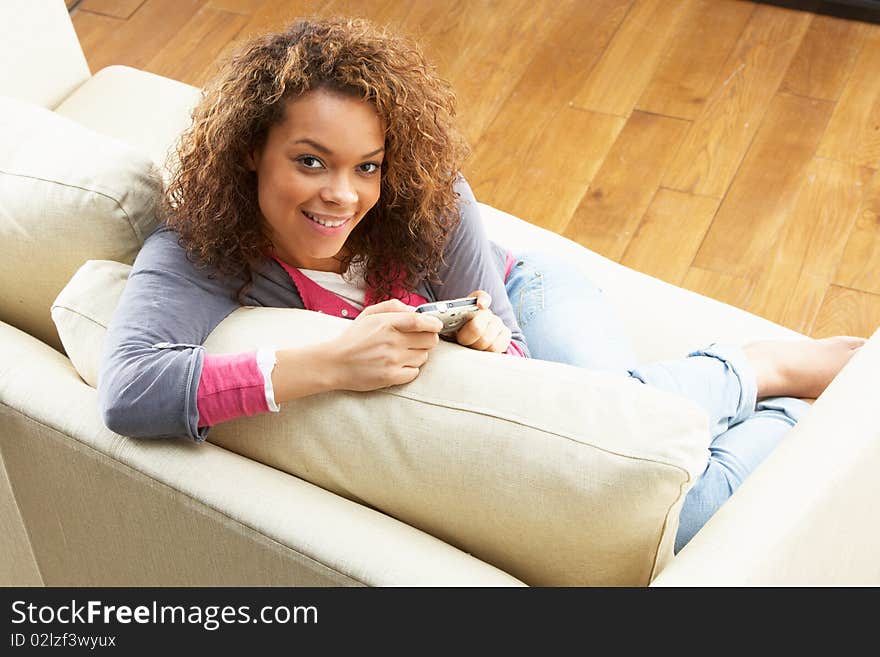 Woman Looking At Pictures On Digital Camera Relaxing Sitting On Sofa At Home