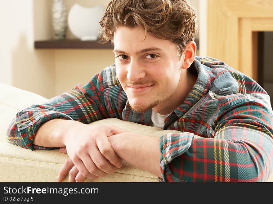 Man Relaxing On Sofa At Home Smiling At Camera