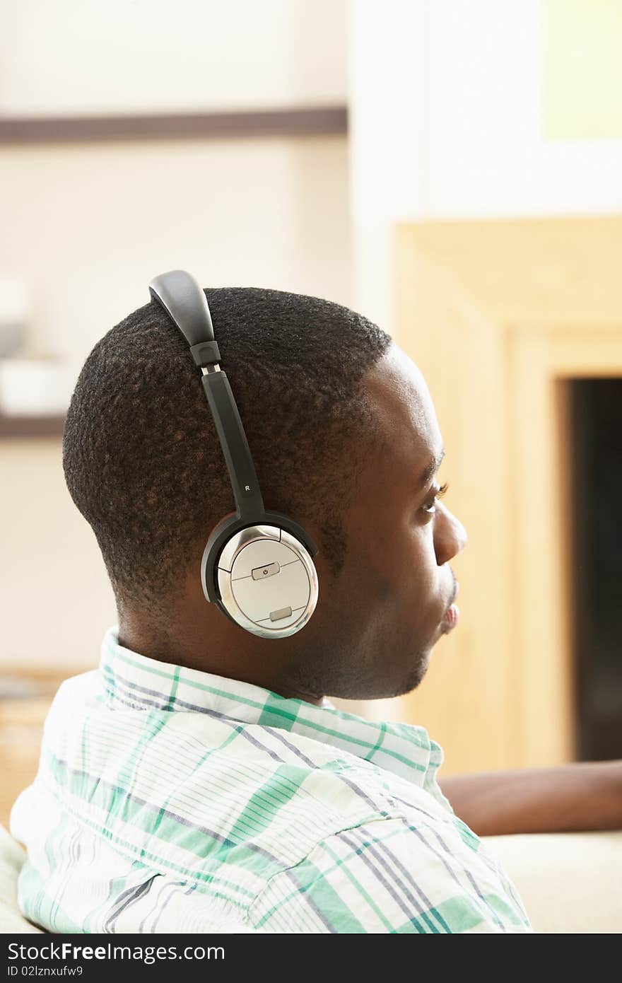 Young Man Relaxing Sitting On Sofa Listening to Music At Home On Headphones