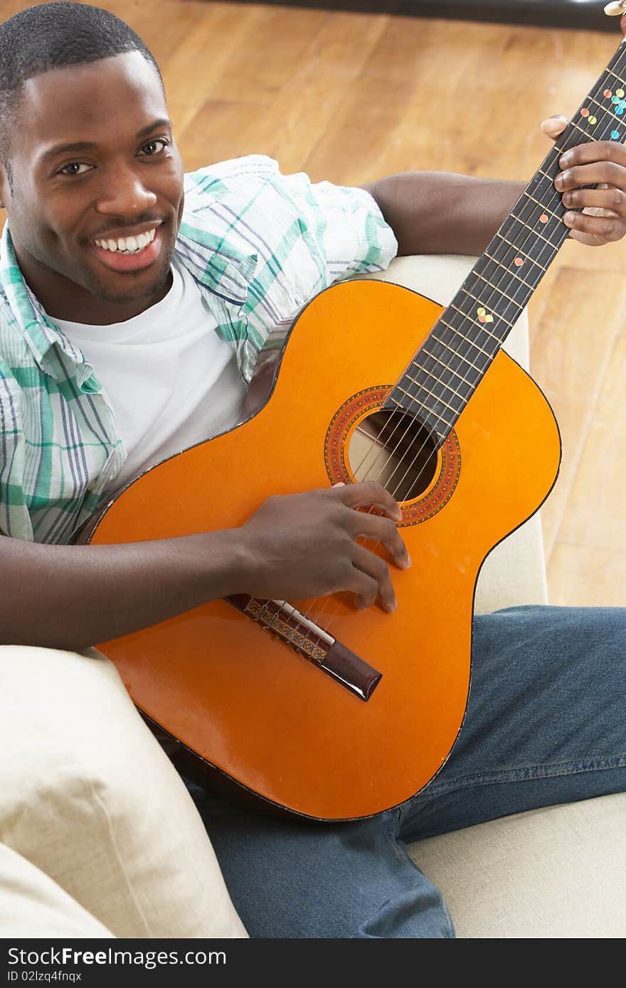 Man Relaxing Sitting On Sofa Playing Guitar