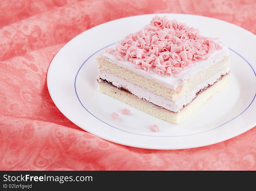 Close up of slice of fresh sweet cake on pink texture