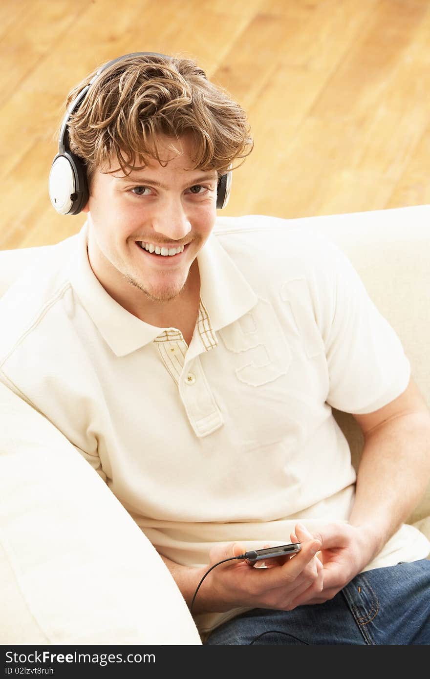 Man Listening To MP3 Player On Headphones Relaxing Laying On Rug At Home