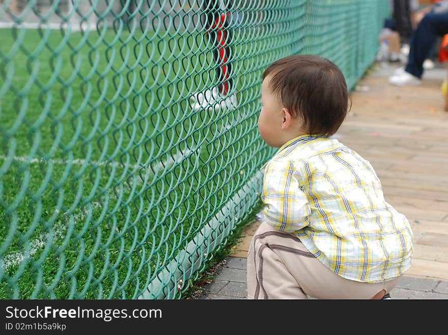 Cute asian baby boy watching football game training. Cute asian baby boy watching football game training