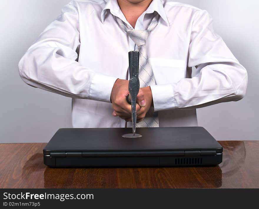 Businessman sitting in the office holding axe cutting up laptop. Businessman sitting in the office holding axe cutting up laptop