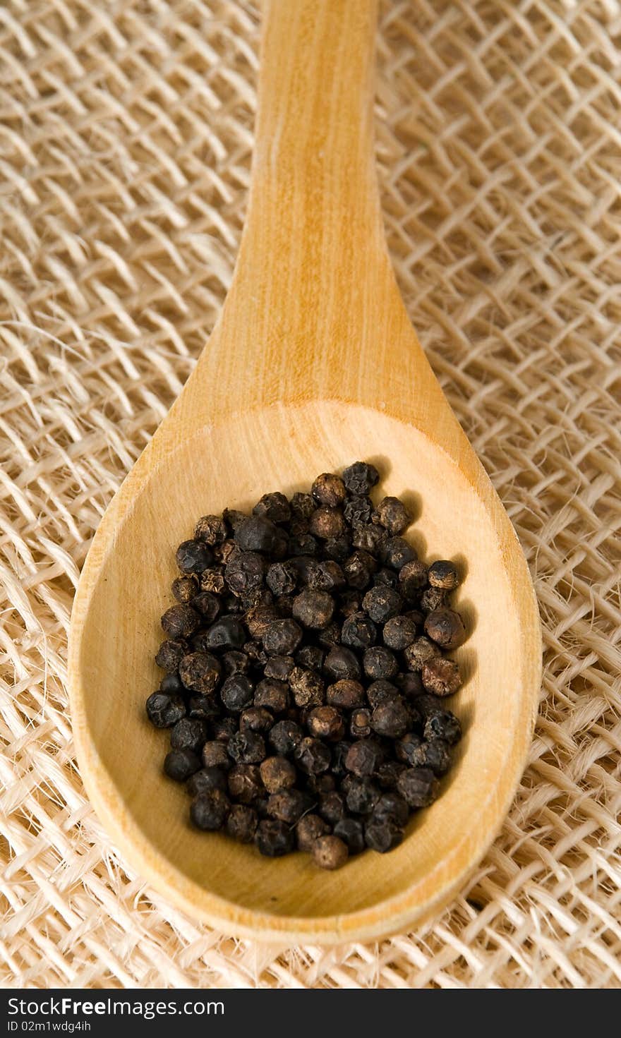 Pepper in a wooden spoon over straw. Pepper in a wooden spoon over straw