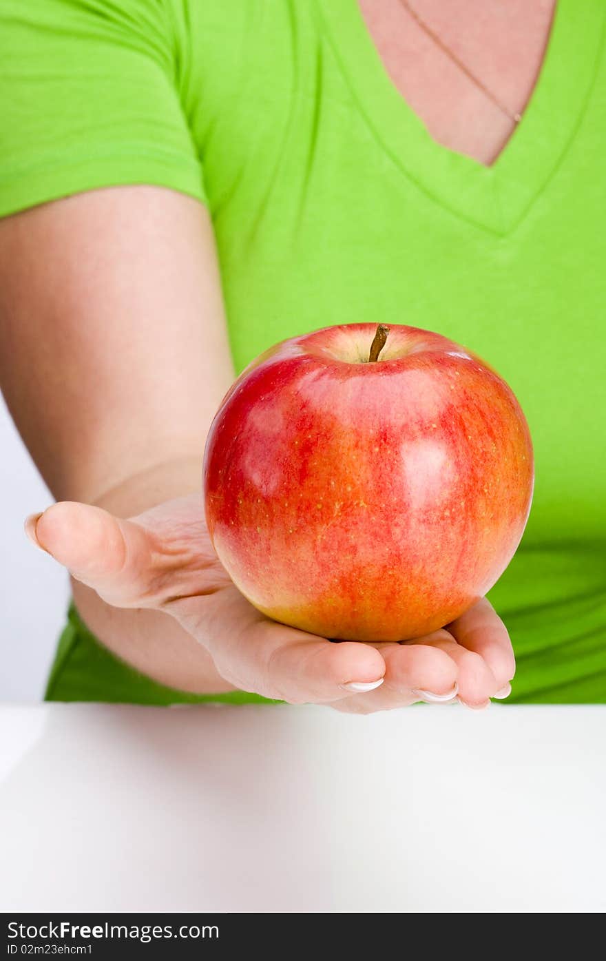 Red apple in hand on green