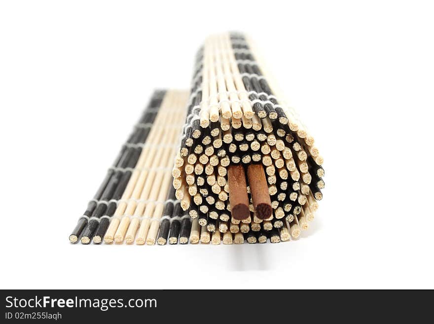 Rolled bamboo mat with a pair of chopsticks isolated on white background. Rolled bamboo mat with a pair of chopsticks isolated on white background