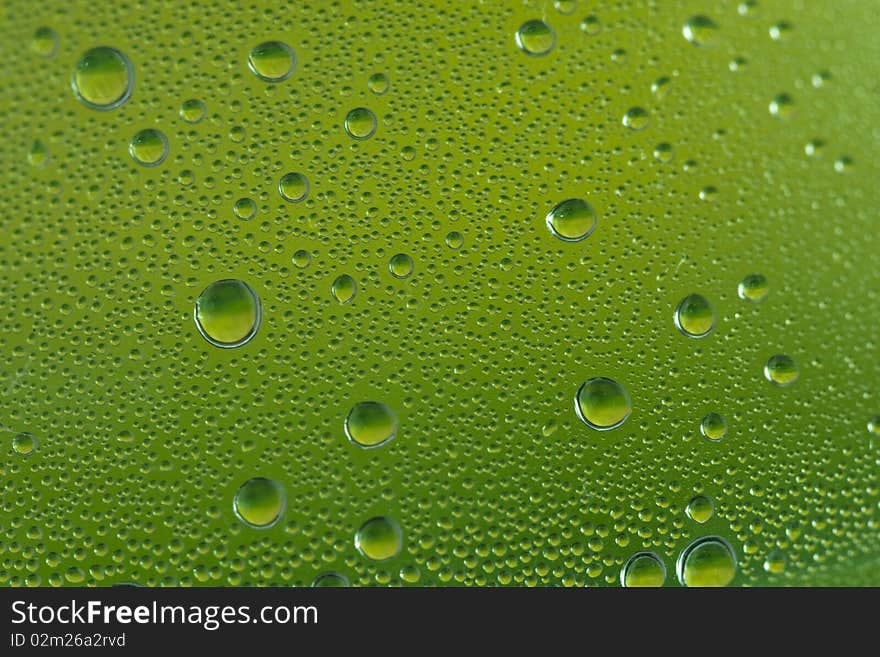 A close up shot of green water droplets on a glass. A close up shot of green water droplets on a glass