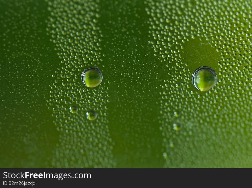 A close up shot of green water droplets on a glass. A close up shot of green water droplets on a glass